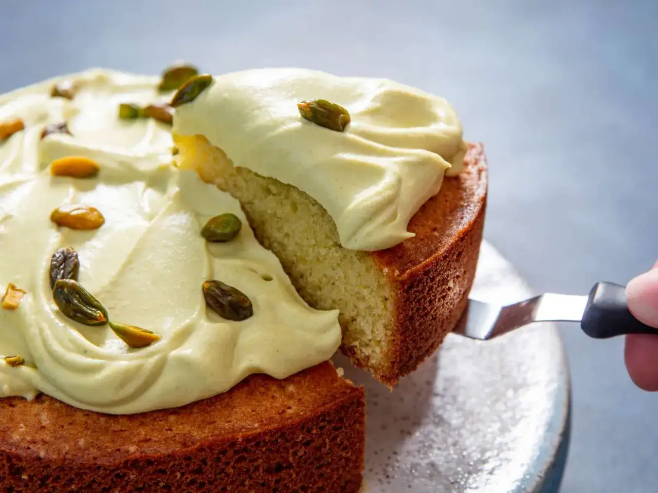 Ein St&uuml;ck Kuchen mit cremiger Pistaziencreme wird herausgeschnitten. Perfekt, um Pistaziencreme selber machen zu lernen!