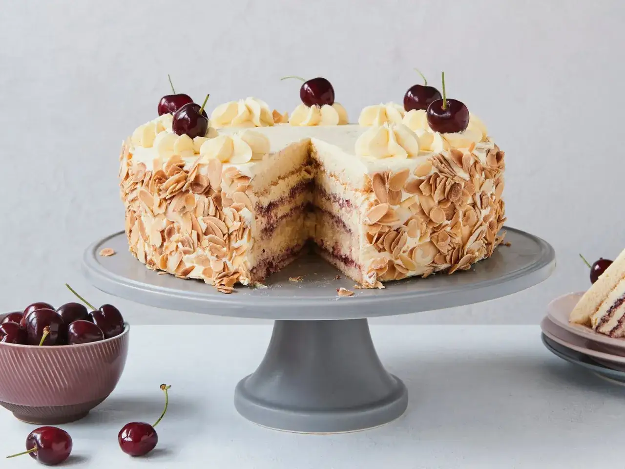 Ein Tortenst&uuml;ck mit Buttercreme mit Pudding, Kirschen und Mandelsplittern.