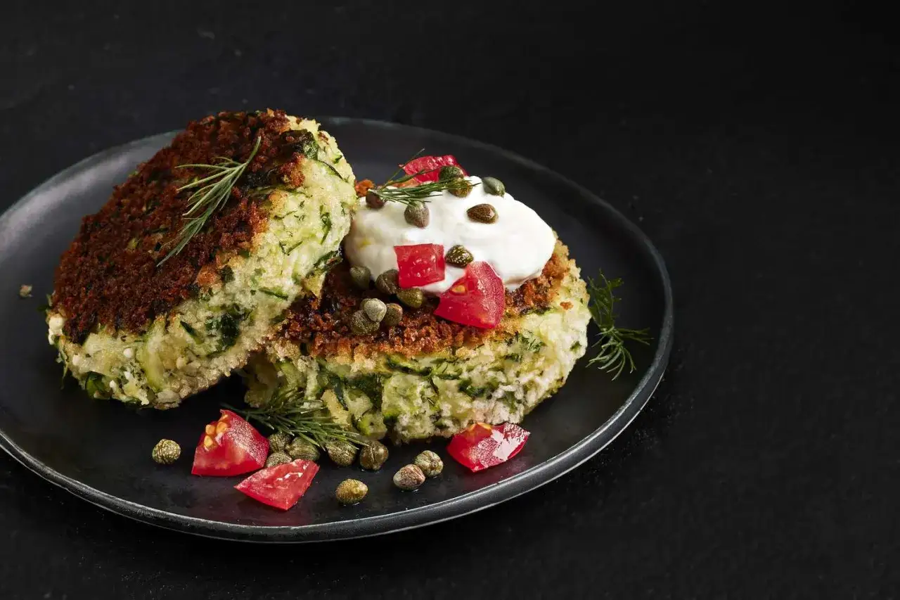 Zwei goldbraun gebackene Zucchini im Teigmantel, garniert mit Joghurt, Tomatenw&uuml;rfeln und Kapern. Ein k&ouml;stlicher Genuss!