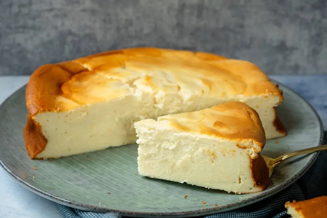 Kuchen mit 250g Quark und Vanillepudding, goldbraun gebacken, auf einem Teller mit einem St&uuml;ck abgetrennt.
