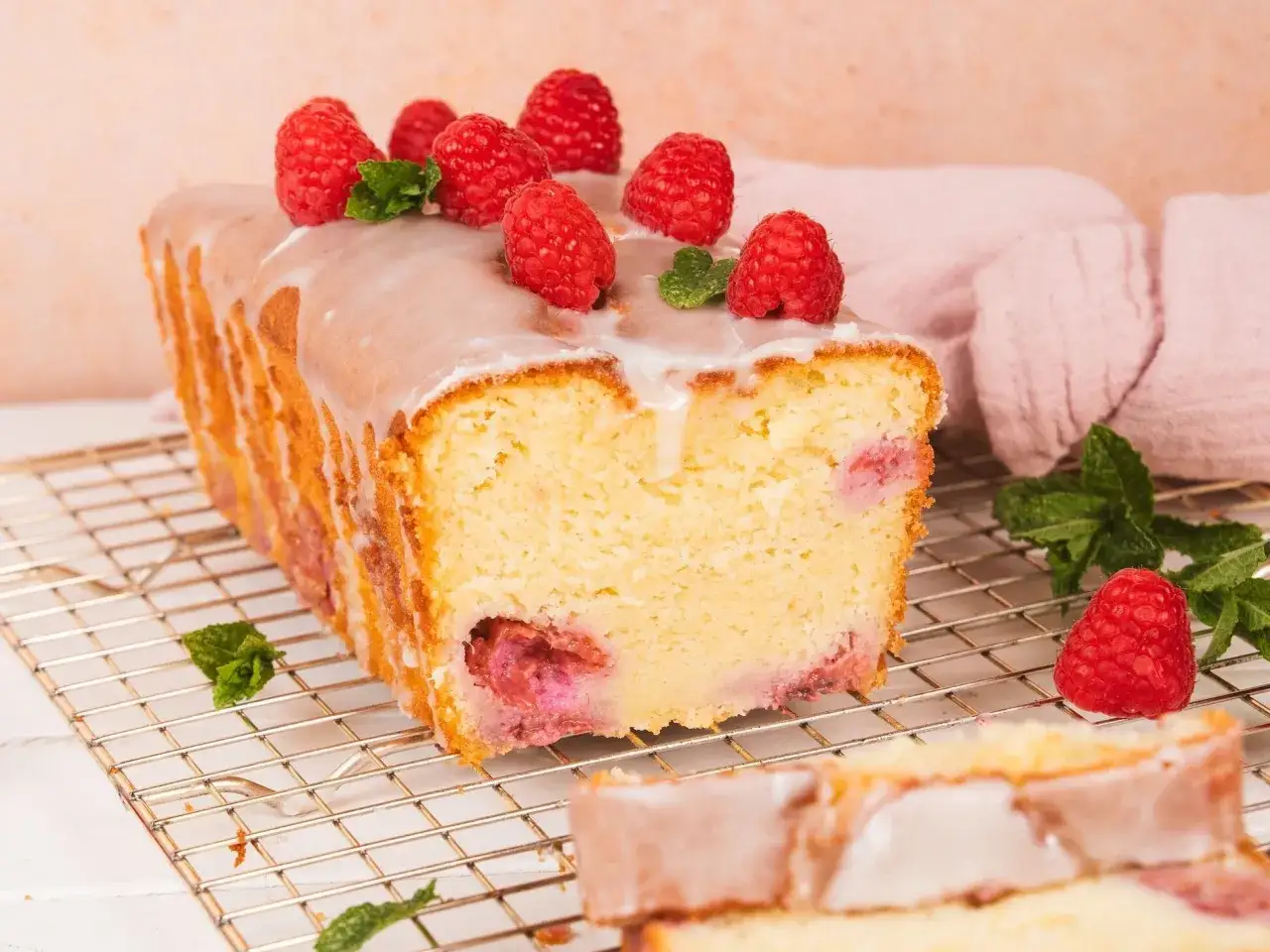 Saftiger Himbeer-Zitronen-Kuchen mit Zuckerguss und frischen Himbeeren, dekoriert mit Minze. Ein Genuss für jeden Anlass.