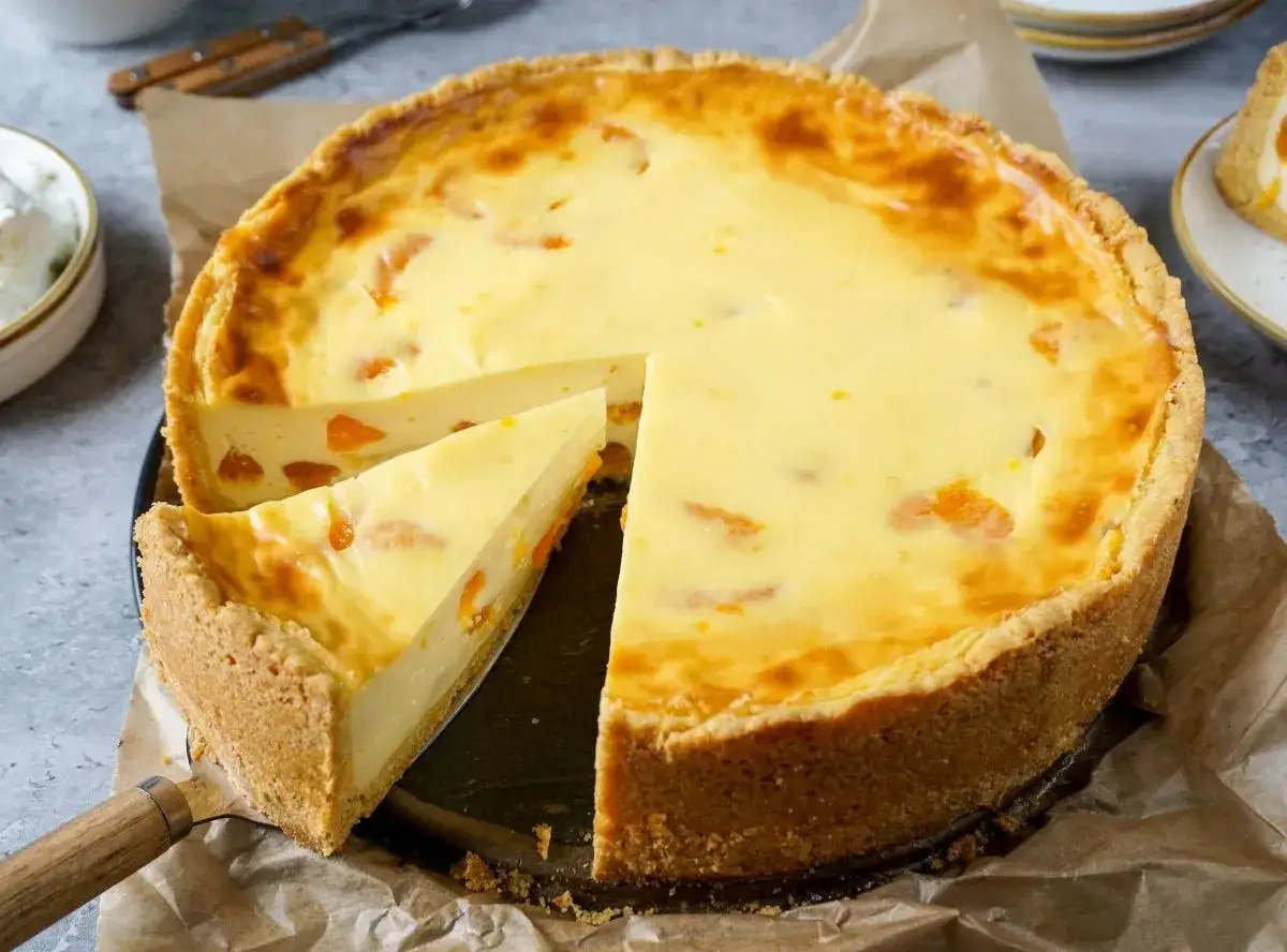 Ein saftiger Mandarinen Schmand Kuchen vom Blech, mit einem St&uuml;ck herausgeschnitten, zeigt seine cremige F&uuml;llung und den knusprigen Boden.