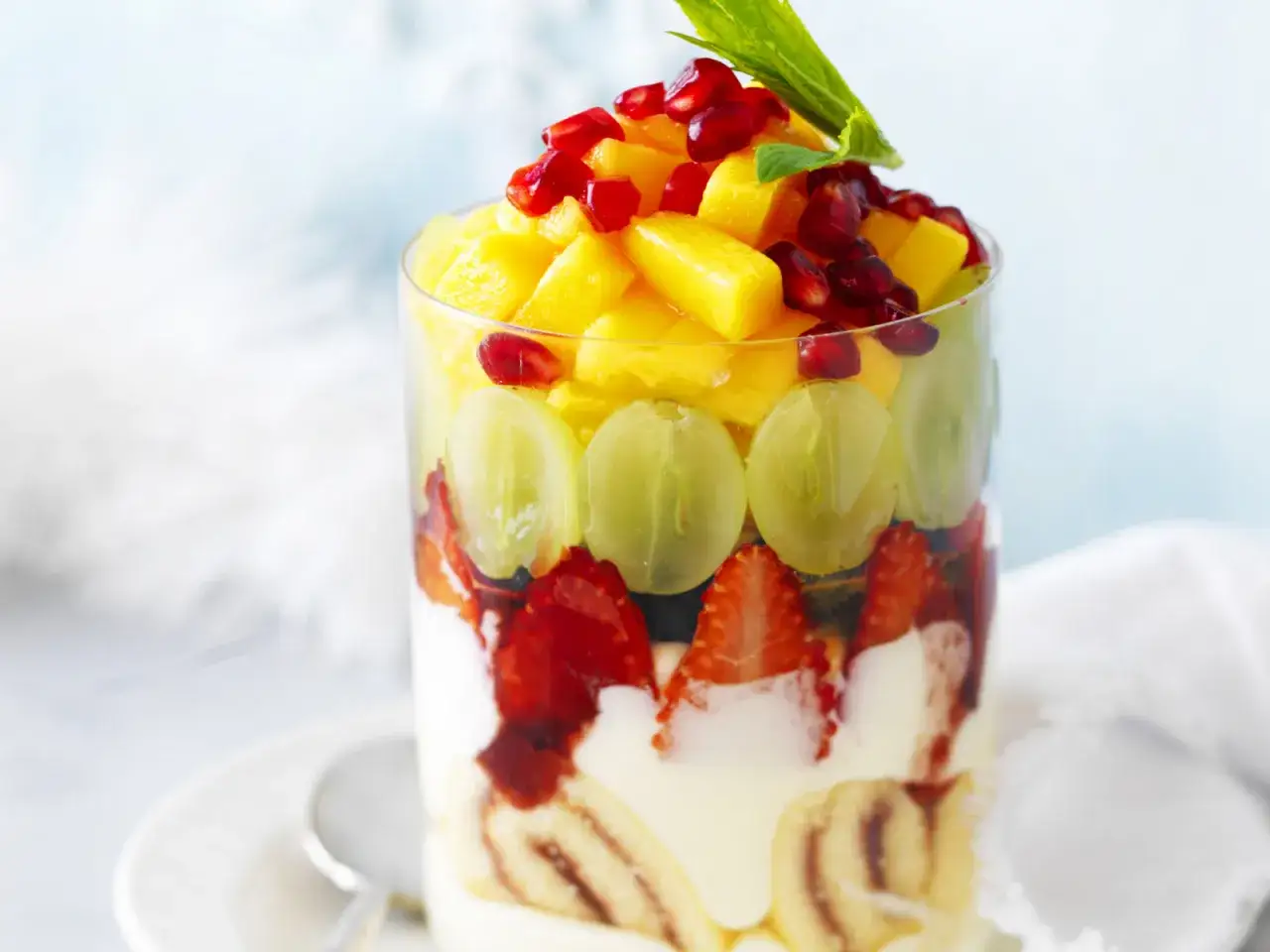 Fruchtiger Becher mit Mango, Granatapfel, Trauben, Erdbeeren und Banane. Ein schnelles und einfaches Sommer Dessert.