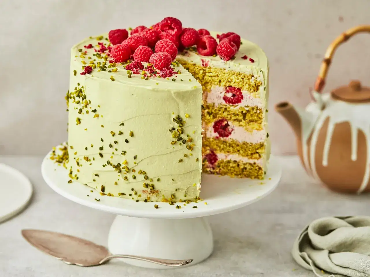 Eine k&ouml;stliche Pistazien Himbeer Torte, &uuml;ppig garniert mit frischen Himbeeren und gehackten Pistazien.