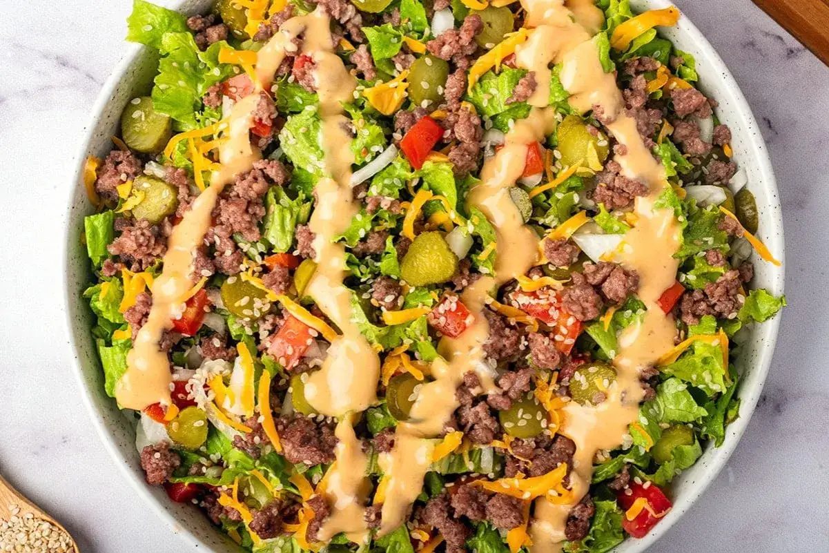 Ein k&ouml;stlicher Big Mac Salat mit Hackfleisch, Salat, Gurken, Tomaten, Zwiebeln und K&auml;se, betr&auml;ufelt mit einer cremigen Sauce.