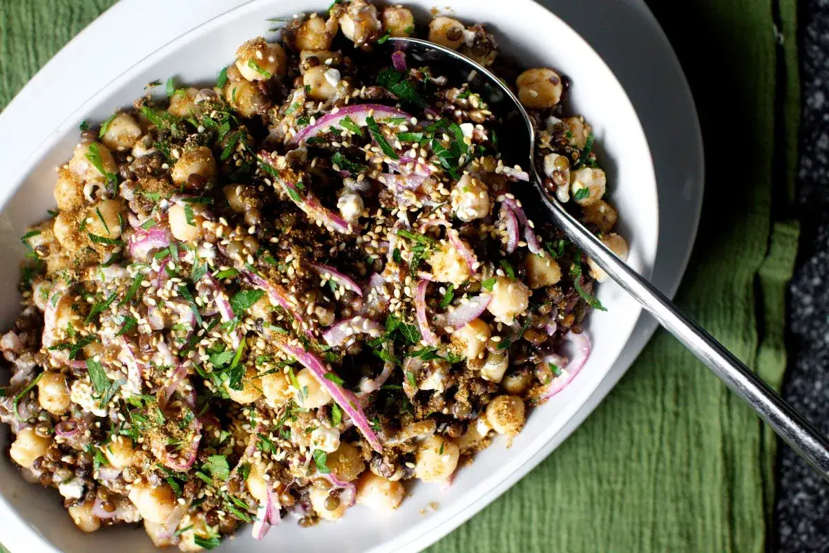 Ein Linsensalat mit Kichererbsen, roten Zwiebeln und Kr&auml;utern, bestreut mit Sesam und Gew&uuml;rzen. Raffinierte Rezepte mit Linsen sind oft so k&ouml;stlich.