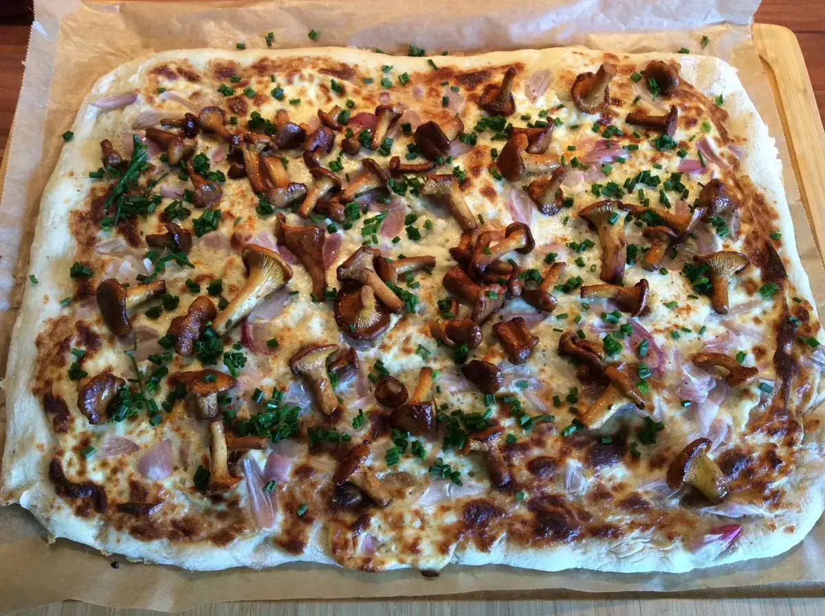 Flammkuchen mit Pfifferlingen, Zwiebeln und Schnittlauch. Ein k&ouml;stlicher Genuss f&uuml;r Pilzliebhaber.