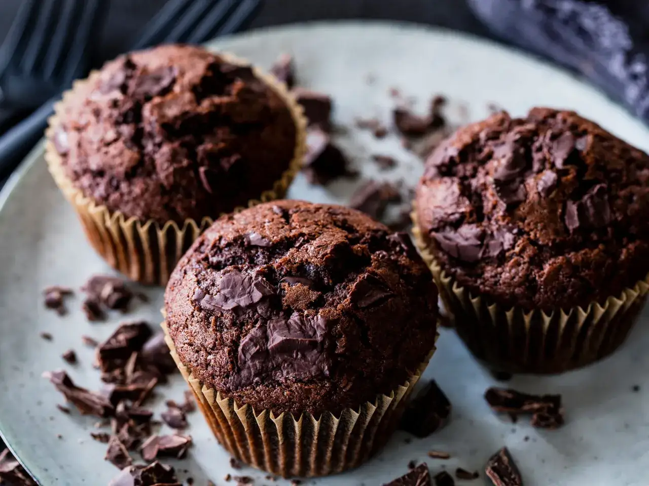 Drei saftige Schokomuffins mit Schokostückchen, perfekt für ein schnelles schokomuffins rezept.