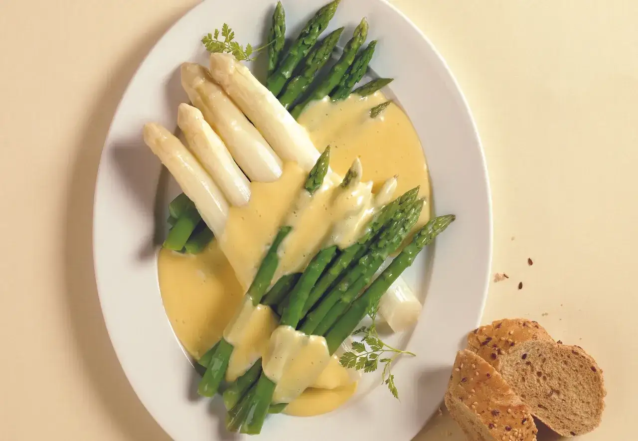 Spargel, weiß und grün, übergossen mit cremiger Sauce Hollandaise, garniert mit Petersilie. Dazu Brot.