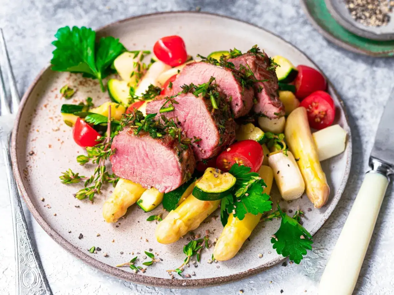 Saftiges rosa gebratenes Schweinefilet mit wei&szlig;em Spargel, Zucchini und Kirschtomaten. Ein Gericht, das man zu Ostern essen kann, top 7!