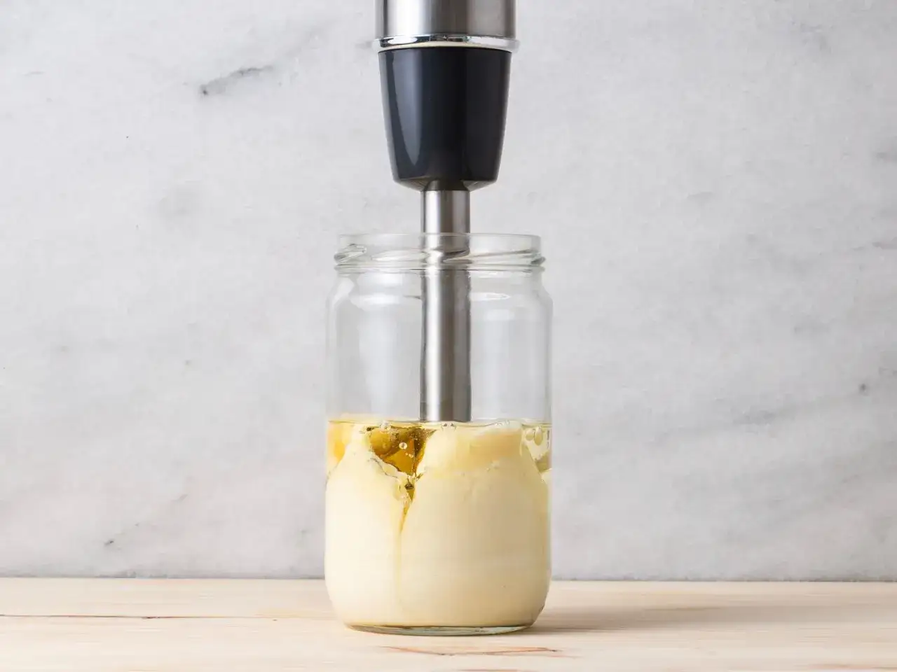 Ein Stabmixer mixt &Ouml;l und Eigelb in einem Glas. So einfach gelingt das Mayonnaise Rezept.