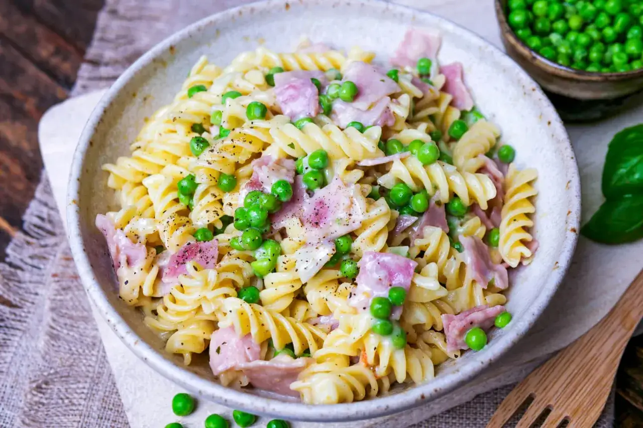 Fusilli-Nudeln mit Erbsen und Schinken in cremiger Schinken Sahne Sauce, bestreut mit Pfeffer.