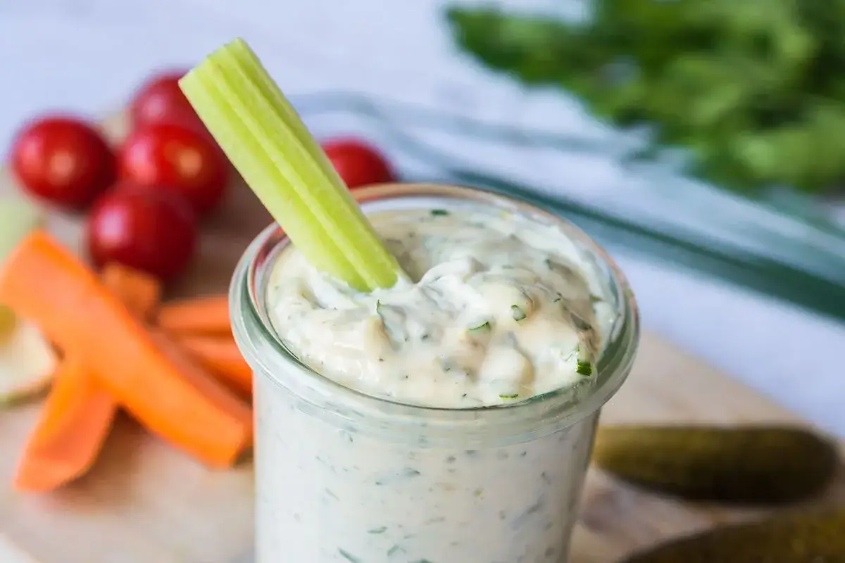 Ein Selleriest&auml;ngel taucht in cremige Remoulade. Das Remoulade Rezept Original ist perfekt f&uuml;r Gem&uuml;sesticks und Gurken.