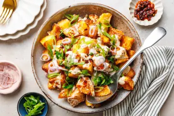 Kartoffelsalat mal anders: knusprige Kartoffelspalten mit cremiger Sauce, Frühlingszwiebeln und roten Zwiebelringen in einer rustikalen Schüssel.