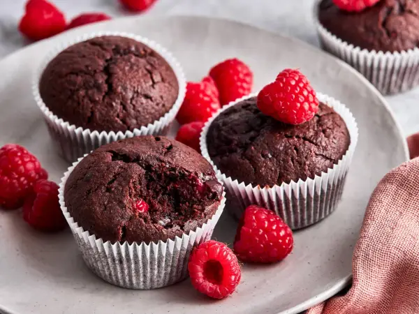 Saftige schoko himbeer muffins auf einem Teller, garniert mit frischen Himbeeren. Ein Genuss für alle Sinne!