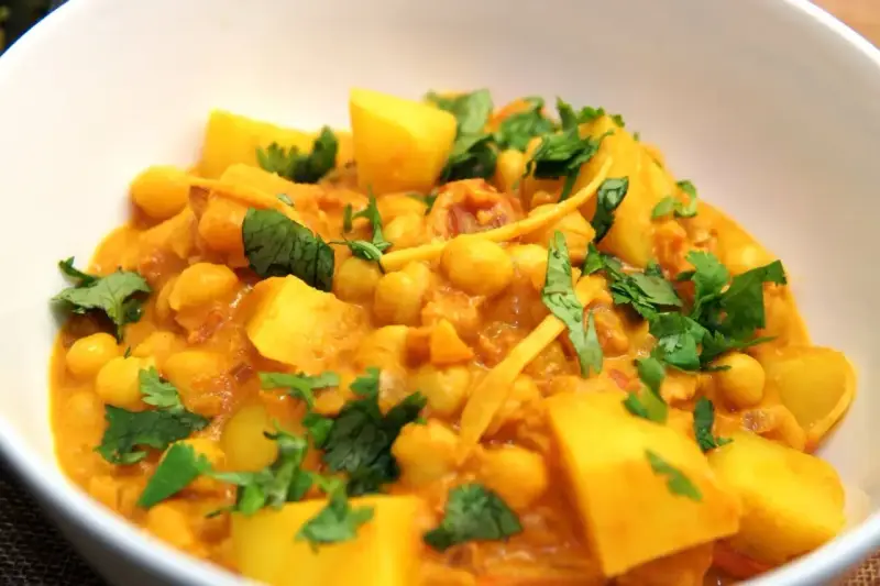 Herzhaftes Kichererbsen Curry mit Kartoffelstücken und frischem Koriander, ein Genuss für die Sinne.