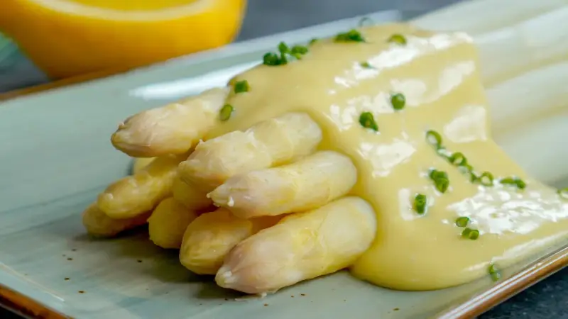 Spargel mit cremiger Sauce Hollandaise, garniert mit Schnittlauch. Ein Klassiker der Frühlingsküche.