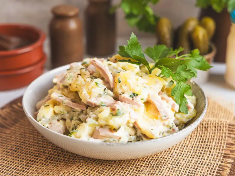 Schüssel mit Kartoffelsalat mit Miracel Whip, Schinken und Petersilie. Dazu passen Gewürzgurken.