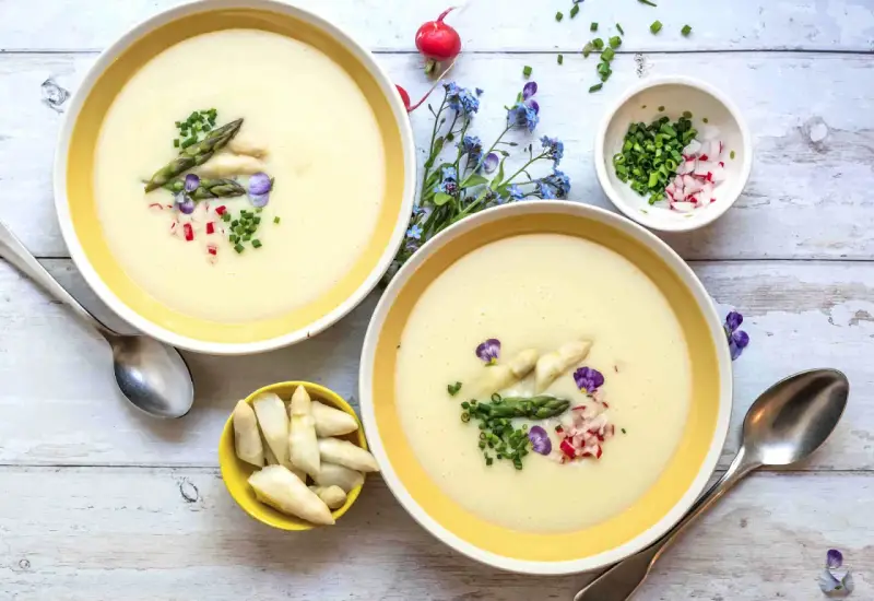 Cremige Spargelsuppe, ein einfaches Rezept für den Frühling. Garniert mit Spargelspitzen, Radieschen und Schnittlauch.