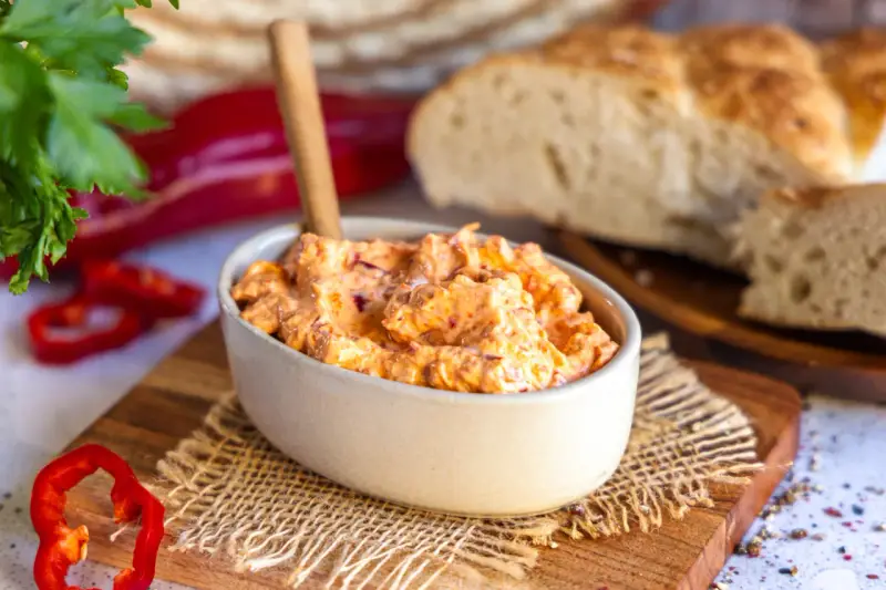 Cremiger Ajvar Feta Dip mit frischer Petersilie und Paprika, serviert mit rustikalem Brot.